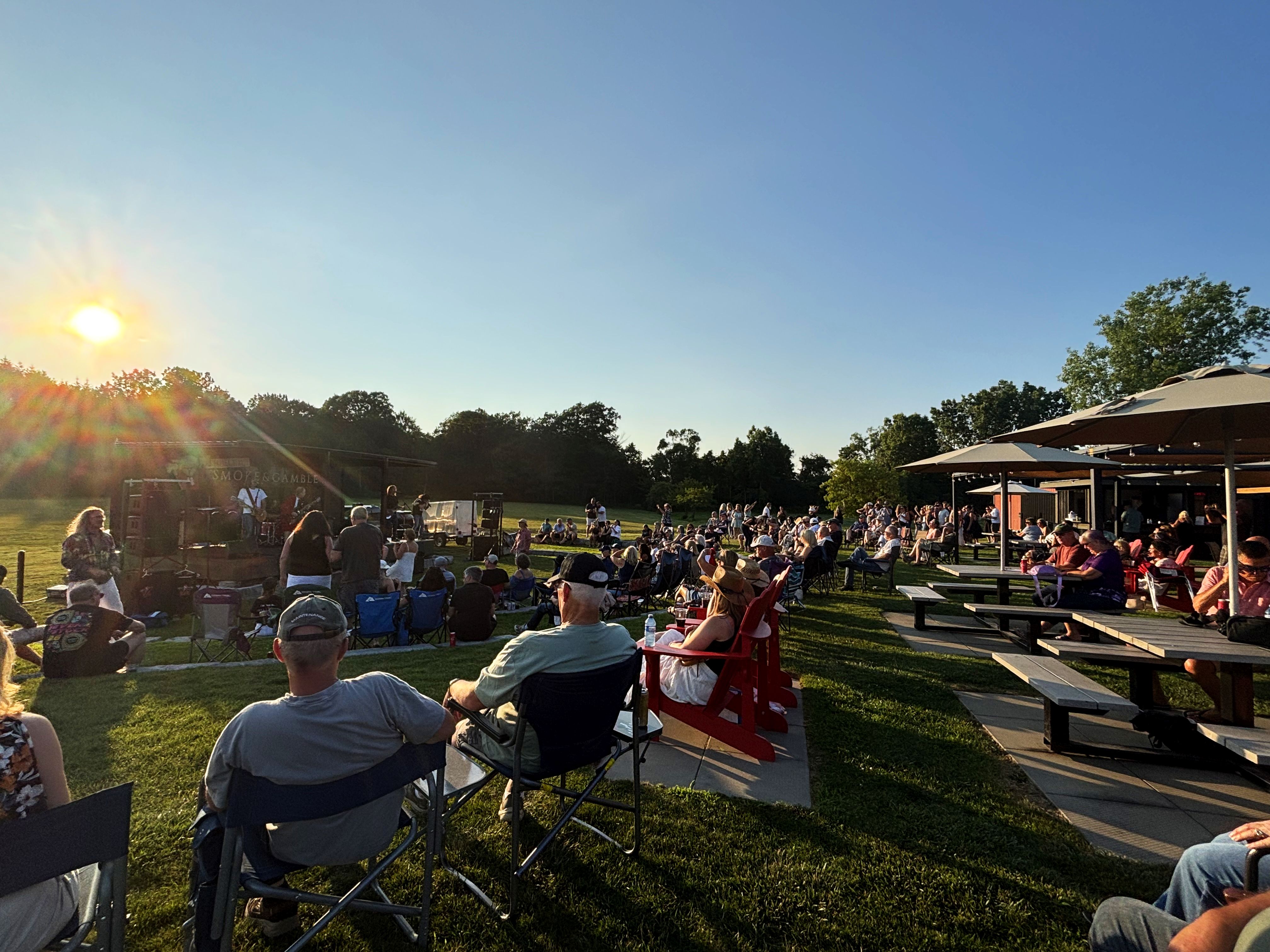 a group of people enjoying an outside patio concert during the sunset at Frisky Beavers